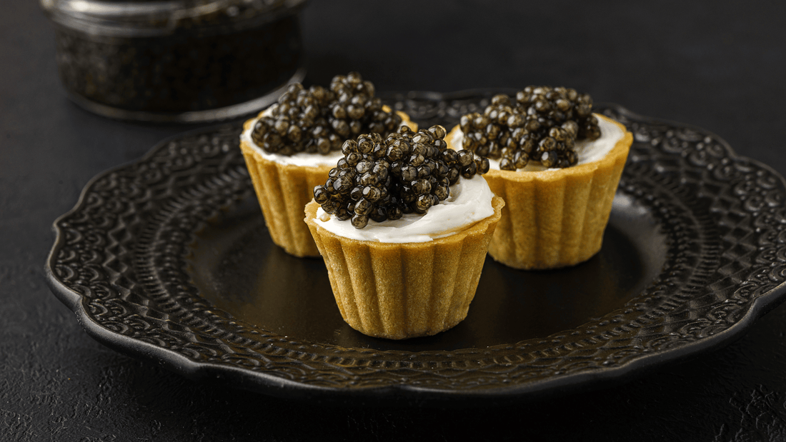 Bowl of cacio e pepe pasta topped with dark caviar on a simple wooden table