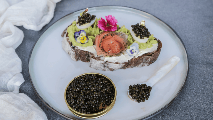 Soft-boiled egg cut open in an eggcup, topped with dark caviar, morning light